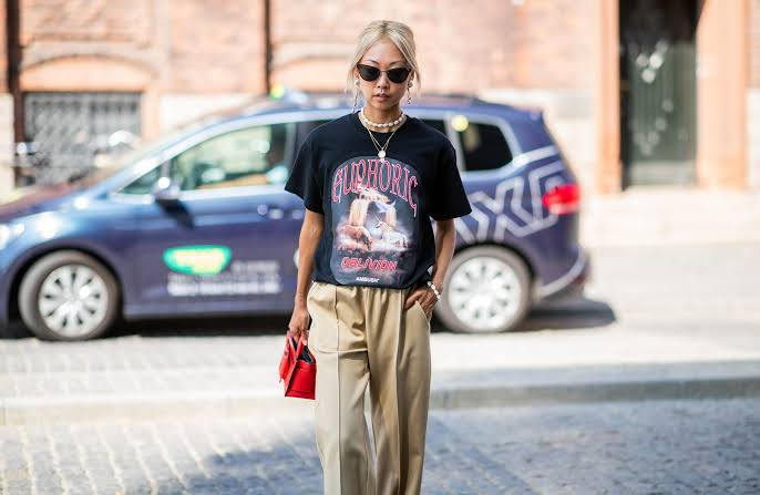 Person wearing graphic tee outfits with denim and layered jacket